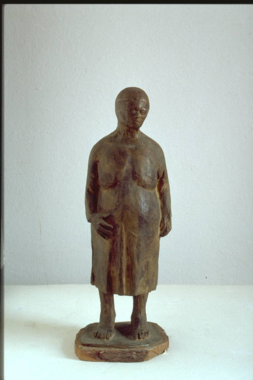 Maternità, Figura femminile, incinta, in piedi, con una mano appoggiata sul ventre (scultura) di Thusek, Gina (terzo quarto sec. XX)