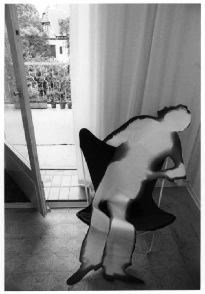 Sagoma in carta di figura maschile accomodata su una sedia accanto alla finestra