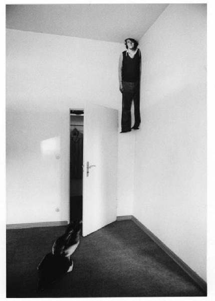 Sagoma in carta che raffigura l'autore attaccata al soffitto di una stanza e sagoma di figura femminile nuda sdraiata sul pavimento