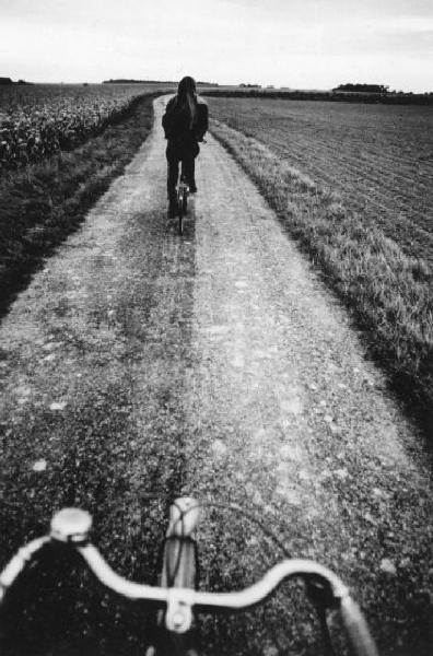 Donna in bicicletta lungo una stradina di campagna