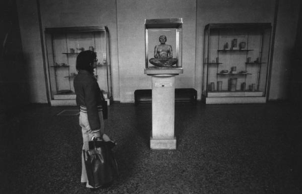 Museo - donna osserva statua in una teca