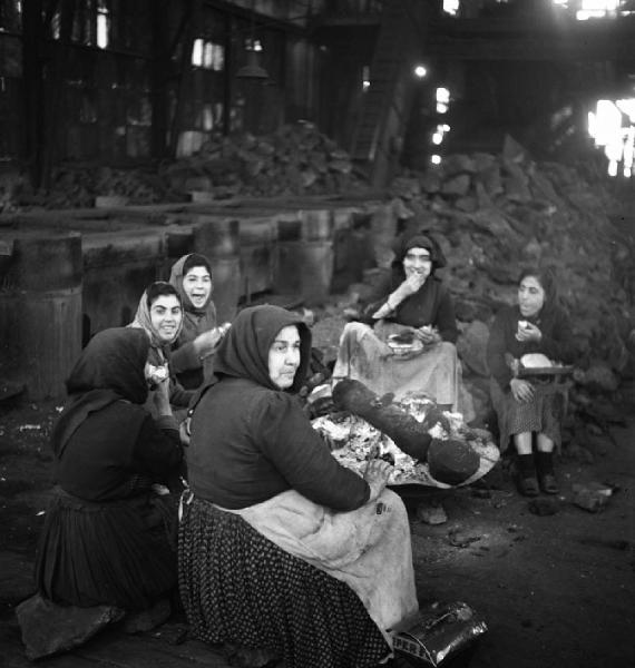 Italia del Sud. Sardegna, Carbonia - Miniera di carbone - Capannone, interno - Ritratto di gruppo: donne addette alla cernita del carbone (dette cernitrici) - Pausa pranzo