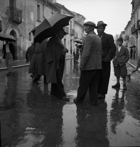 Italia del Sud. Calabria - uomini in conversazione sotto la pioggia