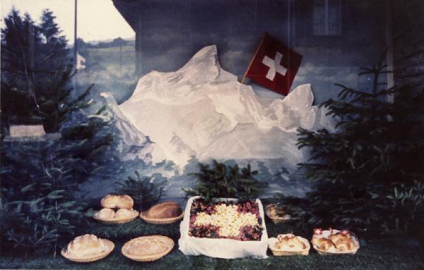 Kodachrome. Hergiswil - Vetrina di un panettiere - Forme di pane - Disegno delle alpi svizzere - Bandiera svizzera - Pini finti