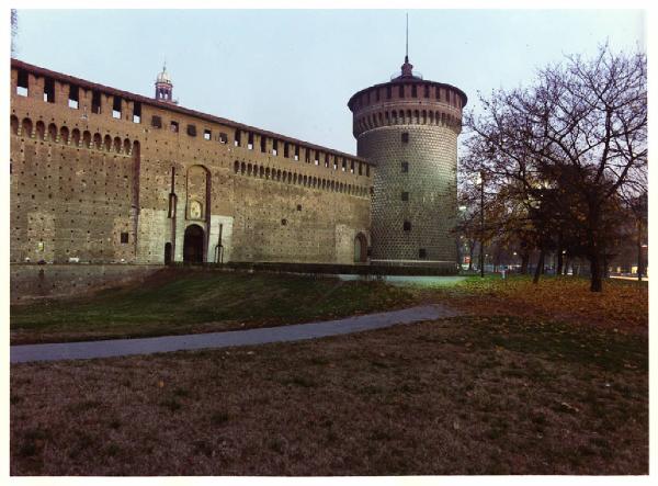 Milano. Castello Sforzesco. Entrata laterale verso piazza Cadorna. Torre d'angolo. Mura esterne. Prato. Alberi. Percorso pedonale