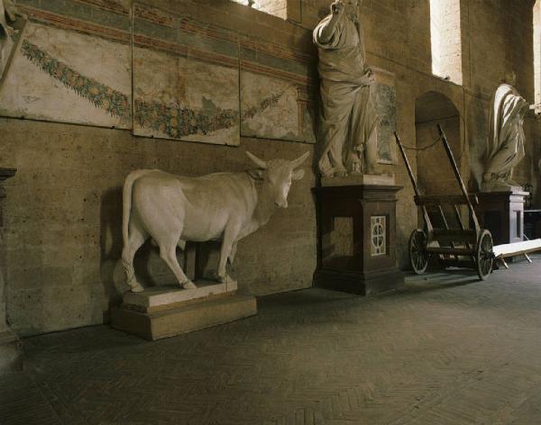 Orvieto dentro l'immagine. Orvieto - Museo Opera del Duomo (?), interno - Statua in marmo di un toro - Due statue di personaggi - Affreschi alle pareti appesi