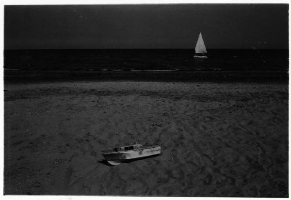 Spiaggia con barca giocattolo e vela in mare sullo sfondo