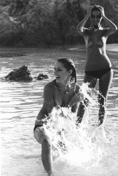 Due donne a seno scoperto giocano in mare