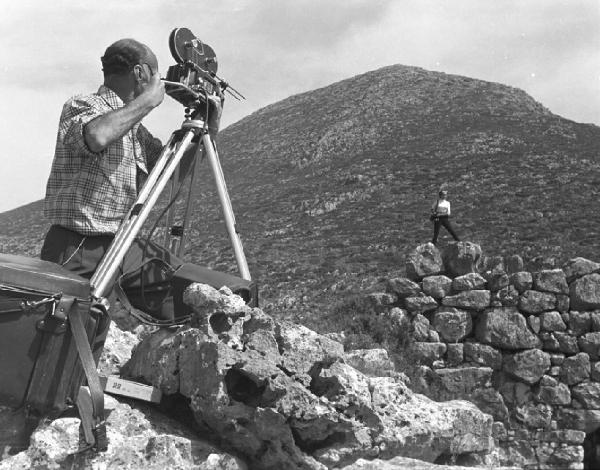 Grecia. L'operatore Hugo Chiesa durante le riprese di "Viaggio nei paesi di Ulisse". Inge Feltrinelli in piedi sul muro sullo sfondo