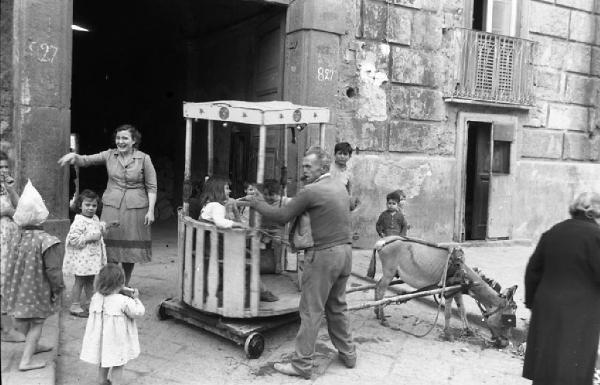 Italia del Sud. Napoli - giostra di fortuna trainata da un asinello - bambini