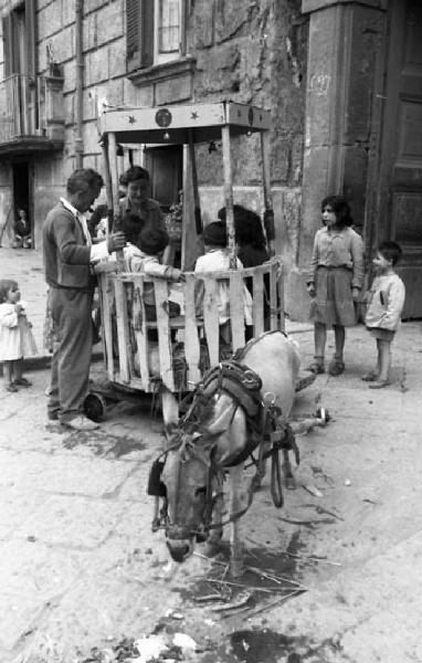 Italia del Sud. Napoli - giostra di fortuna trainata da un asinello - bambini