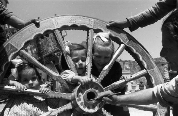 Italia del Sud. Taormina - carretto siciliano - ruota decorata - bambine guardano tra i raggi (iammòzzi)
