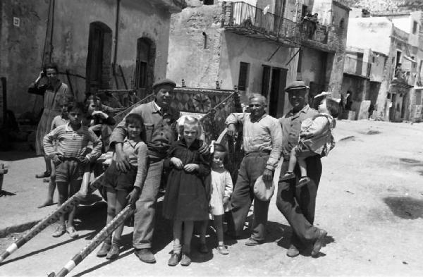 Italia del Sud. Sicilia - ritratto di gruppo - adulti e bambini attorno a un carretto siciliano