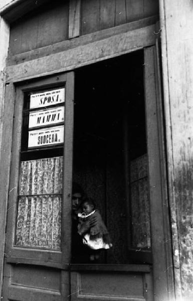 Italia del Sud. Catania - ritratto di coppia - madre e figlio occhieggiano da un portone