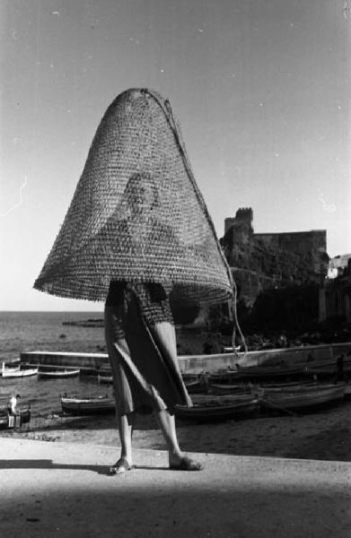 Italia del Sud. Aci Castello - ritratto femminile - donna con nassa in testa