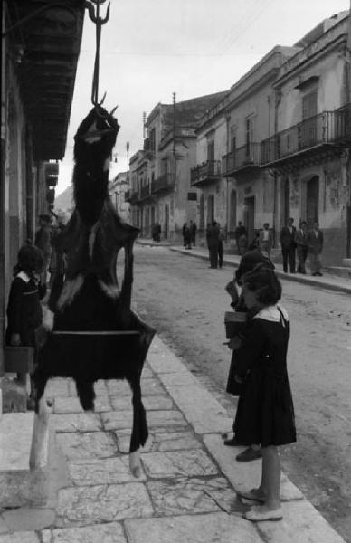 Italia del Sud. Palermo - bambini osservano una pelle di capra appesa per strada