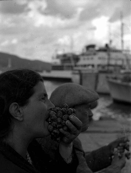 Italia del Sud. traghetto Messina-Reggio Calabria - passeggera mangia un grappolo d'uva [emigrante?]