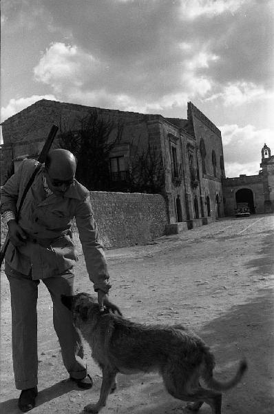 Italia del Sud. Sicilia - borgo fortificato - uomo con fucile accarezza un cane