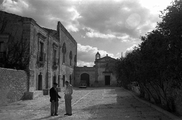 Italia del Sud. Sicilia - borgo fortificato - piazza della chiesa - uomini in conversazione