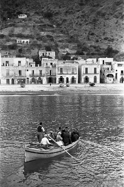 Italia del Sud. Sicilia - Isole Eolie - isola di Lipari - scorcio del borgo di Lipari dal mare - imbarcazione a remi carica di persone