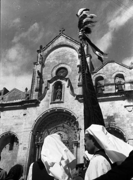 Italia del Sud. Matera - processione dei Santi Medici Cosma e Damiano - associati di una confraternita - confratelli - stendardo - facciata della chiesa di San Giovanni Battista