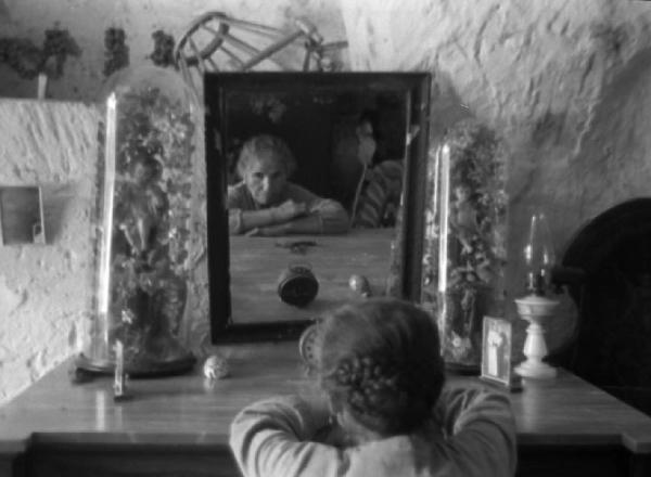 Italia del Sud. Matera - sasso - interno domestico - ritratto femminile - donna anziana riflessa nello specchio