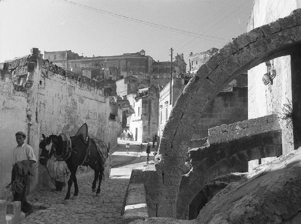 Italia del Sud. Matera - sasso caveoso - scorcio - archi rampanti - ragazzo con mulo da soma