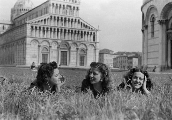 Pisa. Campo dei Miracoli. Tre giovani donne sdraiate sul prato tra il battistero e il duomo