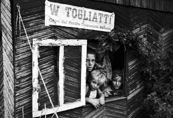 Milano. Baracche alla periferia. Cartello con scritta "W Togliatti" - Bambini affacciati a finestra