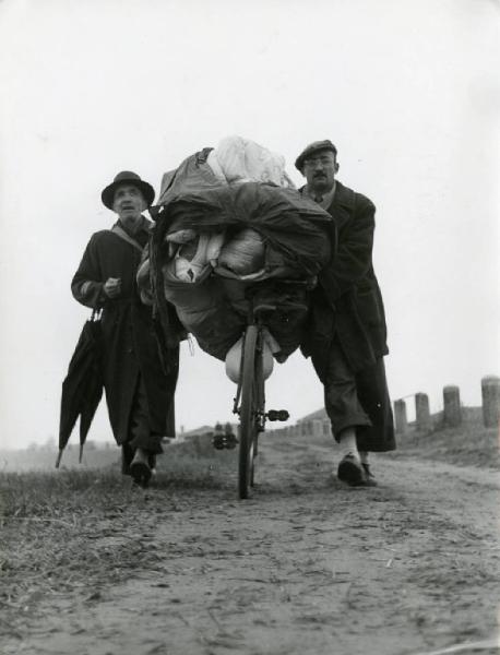 Provincia di Rovigo (?) - inondazione del fiume Po (?) - due uomini - bicicletta carica di oggetti