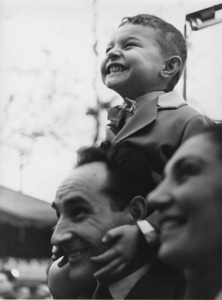Luna park. Milano - Luna park - Ritratto di famiglia: adulto con bambino sulle spalle e volto di donna in primo piano sfocato