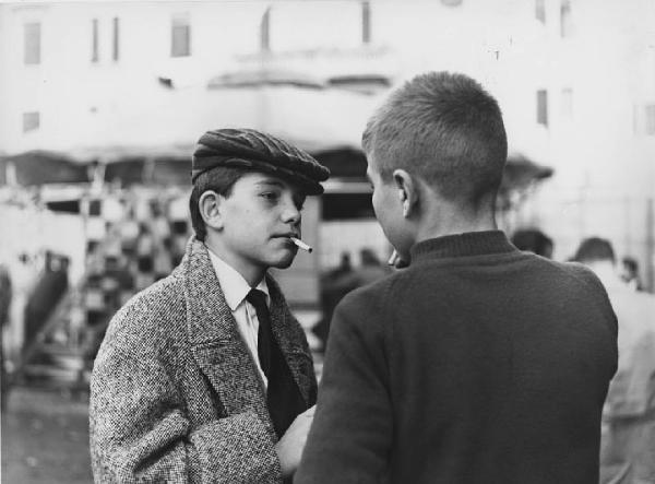 Luna park. Milano - Luna park - Ritratto infantile - Bambino con sigaretta e cappello, coppola davanti a un altro bambino - Fumo - Giostre sullo sfondo