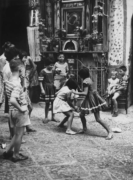 Napoli: Bimbi, scene di vita varie. Napoli - Vicoli - Bambini davanti a un'edicola, cappella votiva alla Madonna - Gioco