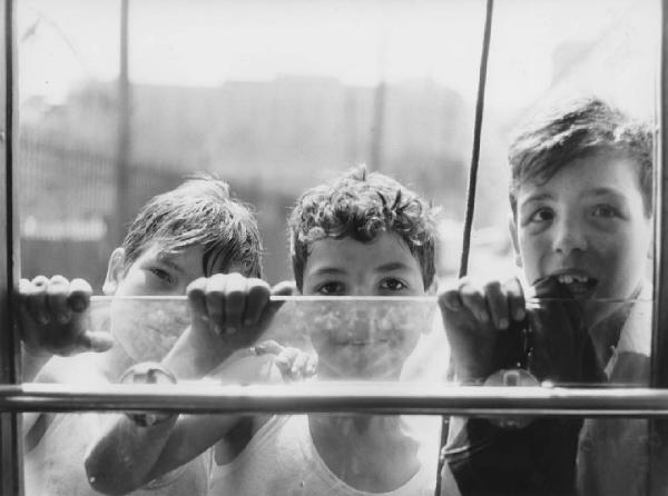 Napoli: Bimbi, scene di vita varie. Napoli - Ritratto di gruppo - Bambini appesi sul retro di un tram con le mani appoggiate al vetro del finestrino