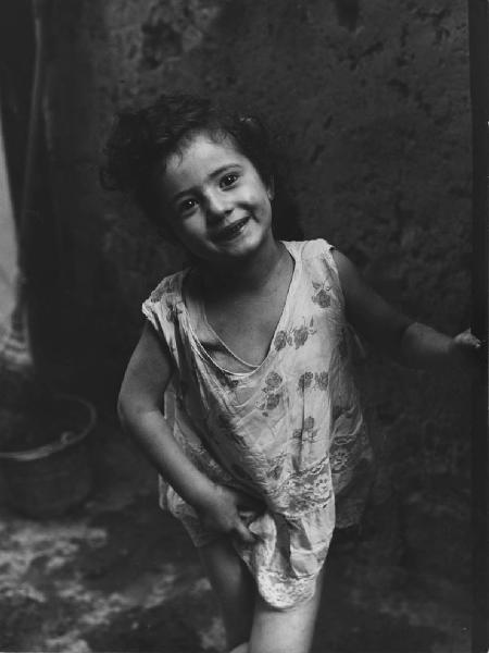 Napoli: Scugnizzi, figure, personaggi. Napoli - Vicoli - Ritratto infantile - Bambina con vestito a fiori - Sorriso