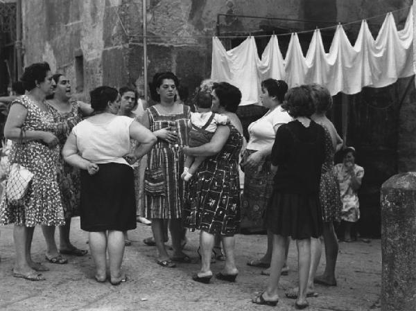 Napoli: Incontri scontri. Napoli - Vicoli - Gruppo di donne di cui una con bambino in braccio - Discussione - Panni stesi