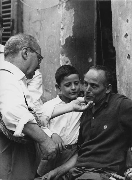 Napoli: Incontri scontri. Napoli - Vicoli - Ritratto di gruppo - Anziano tocca il mento di un uomo - Bambino