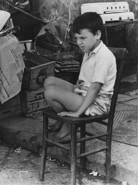 Napoli: Scugnizzi, passatempi. Napoli - Vicoli - Ritratto infantile - Bambino seduto su una sedia