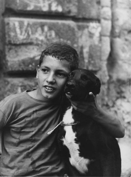 Napoli: Scugnizzi, affetto. Napoli - Vicoli - Ritratto infantile - Bambino in posa con cane - Abbraccio