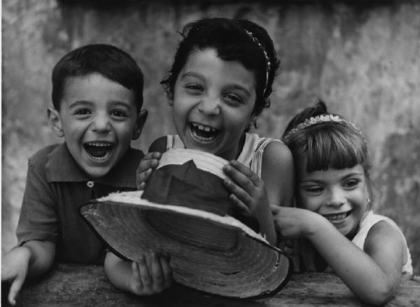 Napoli: Volti figure, ragazze, ragazze/ Bimbi, volti. Napoli - Ritratto di gruppo - Tre bambini vicini con cappello di paglia in mano - Risata