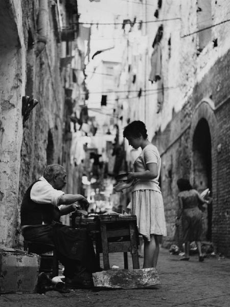 Napoli: Lavoro. Napoli - Vicoli - Ritratto maschile - Anziano calzolaio seduto al banchetto - Ragazza in piedi con scarpe