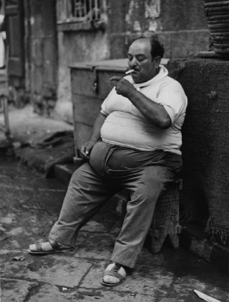 Napoli: Riposo. Napoli - Vicoli - Ritratto maschile - Uomo obeso seduto su una panchina - Sigaretta, fumo
