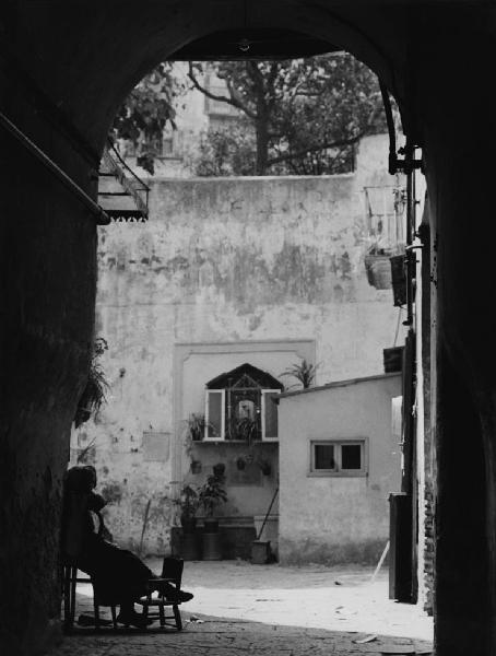 Napoli: Altarini. Napoli - Strada - Arco - Cortile di una casa - Edicola votiva - Anziana seduta su una sedia - Religione