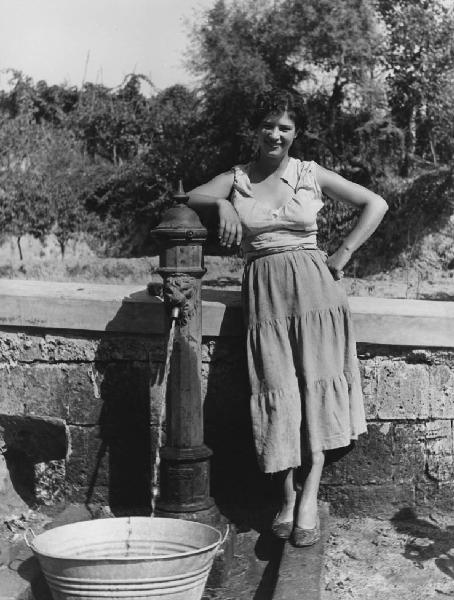 Napoli: Donne. Napoli - Esterno - Ritratto femminile - Ragazza con gonna lunga e maglia di stracci - Fontana - Sorriso - Acqua, secchio