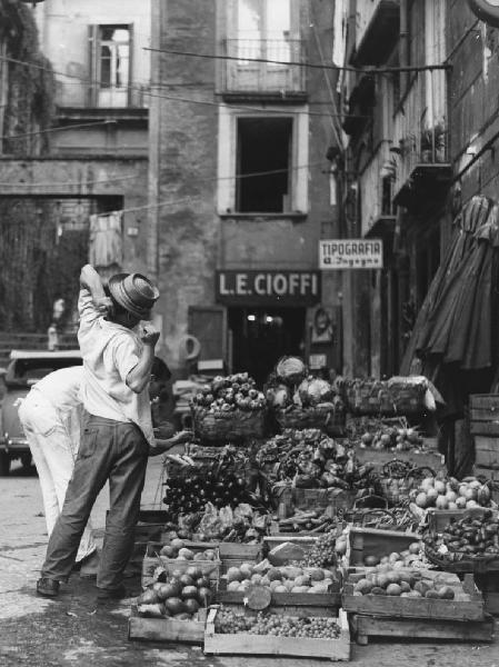 Napoli: Commercio. Napoli - Vicoli - Ritratto maschile - Ragazzo fruttivendolo - Cassette e ceste di frutta e verdura