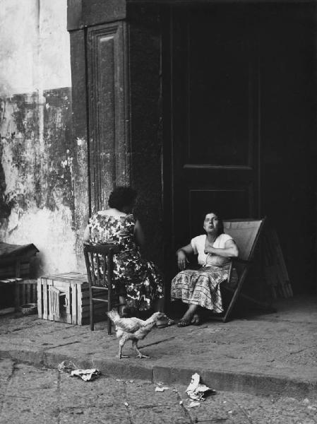 Napoli: Scene di vita varie. Napoli - Vicoli - Ritratto femminile - Donne sull'uscio di casa sedute su sdraio e sedia - Gallina