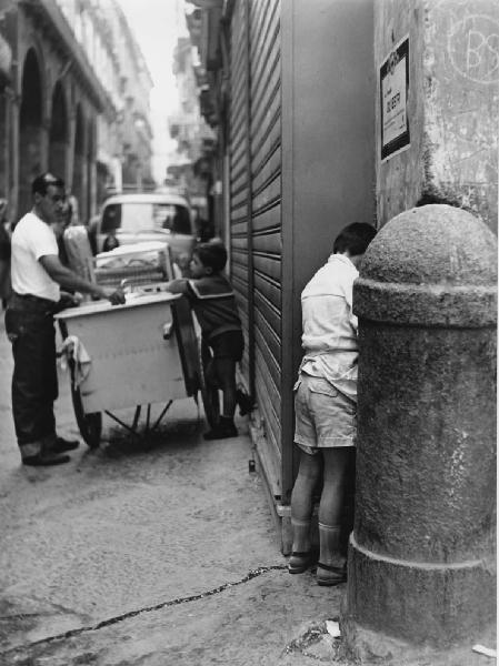 Napoli: Scene di vita varie. Napoli - Strada - Ritratto infantile - Bambino contro un muro dietro un paracarro: urina
