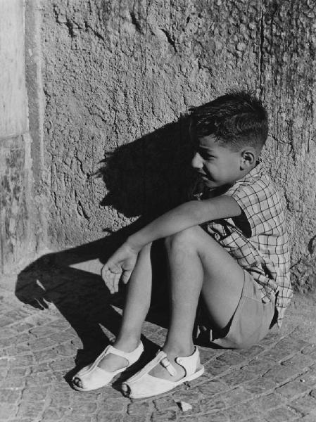Napoli: Bimbi, soli. Napoli - Strada - Ritratto infantile - Bambino seduto a terra contro un muro