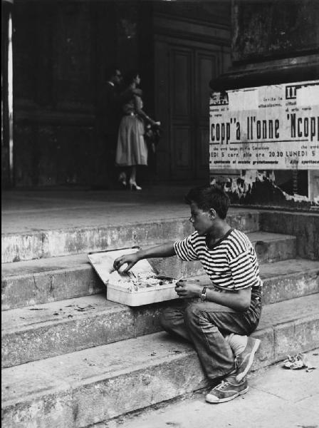 Napoli: Bimbi, soli. Napoli - Strada - Ritratto infantile - Bambino seduto su dei gradini con scatola di caramelle e piccoli oggetti da vendere
