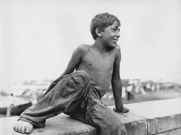Napoli: Bimbi, soli. Napoli - Ritratto infantile - Bambino a torso nudo con jeans su un muretto